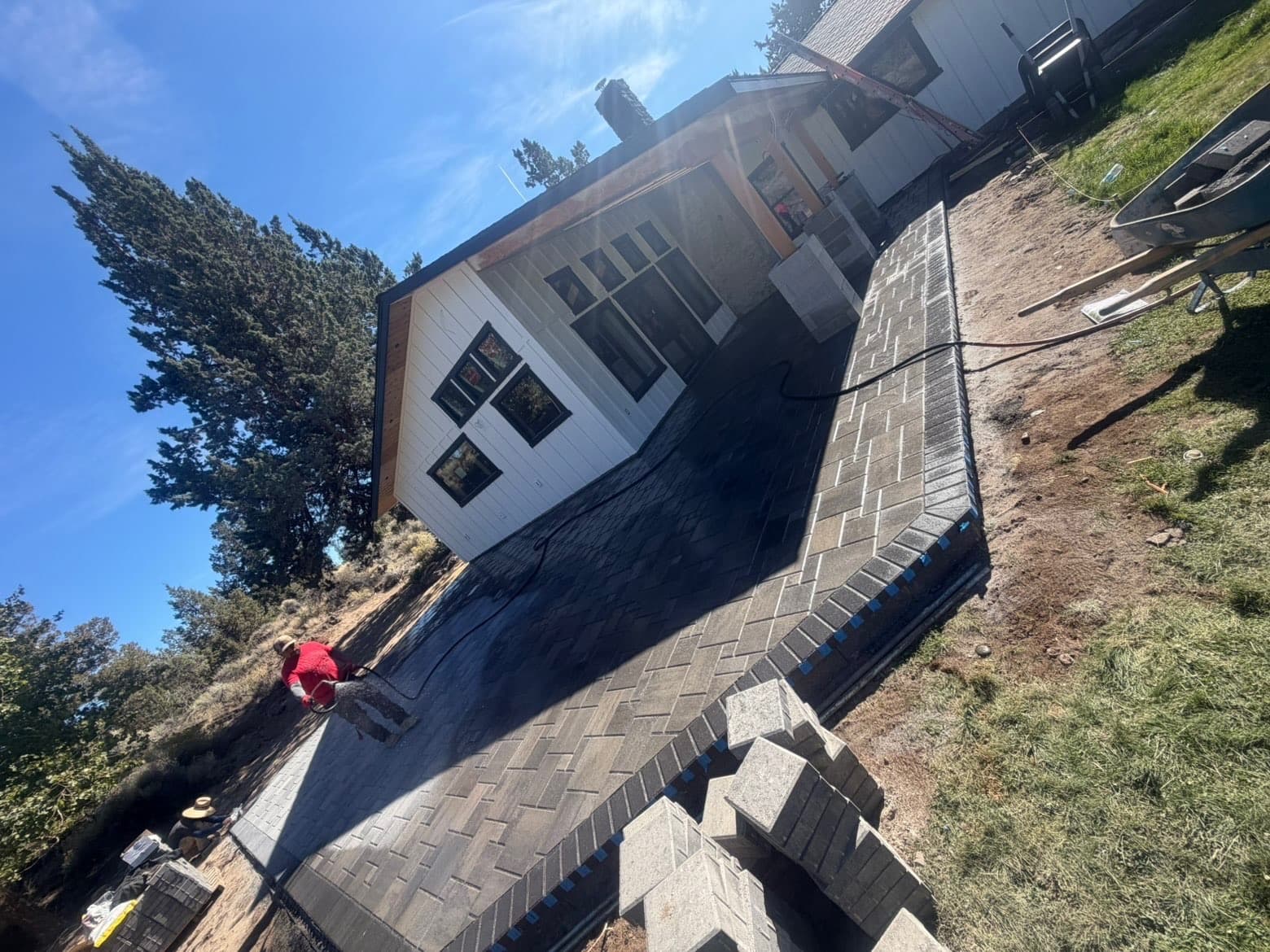 Diagonal view across the back patio showing the paver border wrapping around the corner and masonry bases beneath the porch posts.